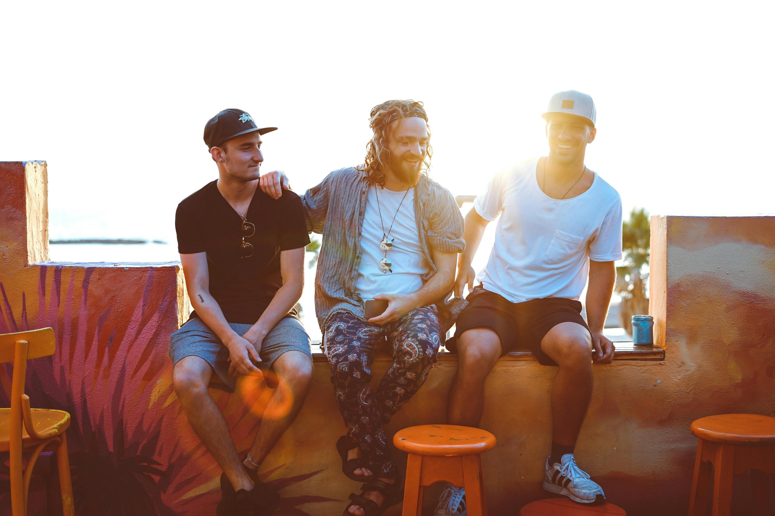 Three friends relax on a Tel Aviv rooftop, soaking up a vibrant sunset atmosphere.